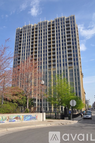 A tall building with many windows is surrounded by trees and a wall with graffiti.
