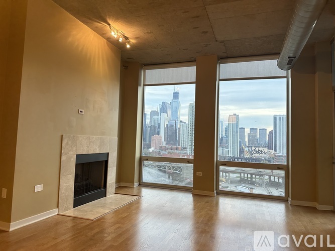 A spacious room with a fireplace and a view of a city skyline through large windows.