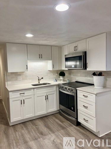 A kitchen with white cabinets and a black stove top oven.