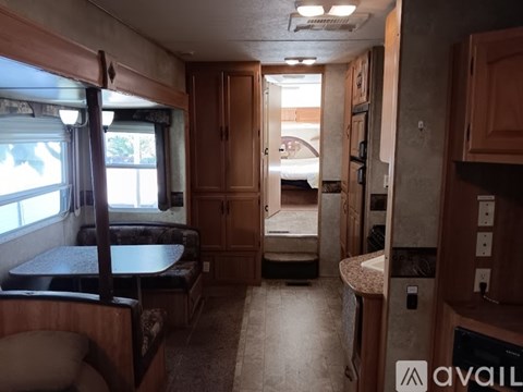 A small, clean RV interior with a bed, table, and cabinets.