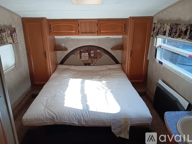 A bedroom with a bed, a window, and a wooden cabinet.