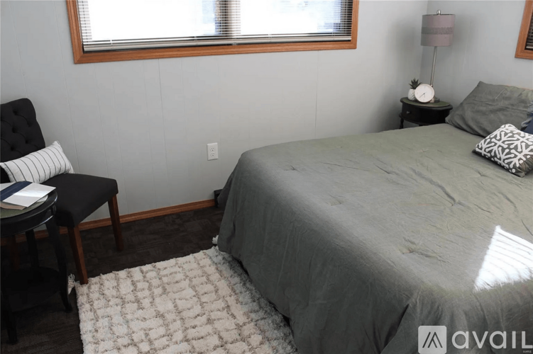 A bedroom with a bed, chair, and lamp.