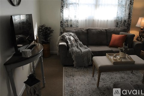 A living room with a grey sofa, a coffee table, and a television on a stand.