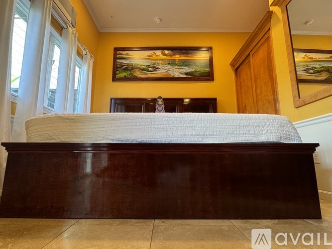 A bedroom with a bed, a wooden cabinet, and a window.