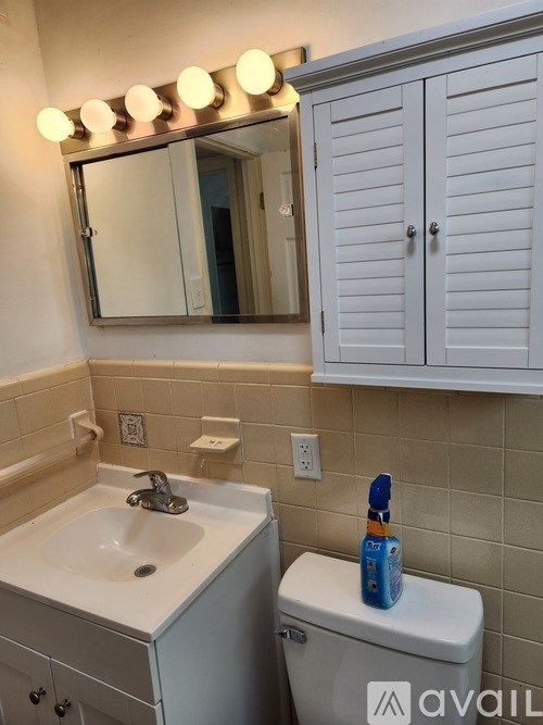 A bathroom with a sink, toilet, and a mirror with lights above it.