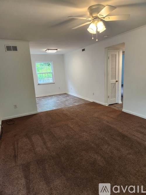 A room with brown carpet and a ceiling fan.
