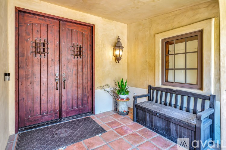 A wooden bench sits in front of a wooden door with a window to the right.