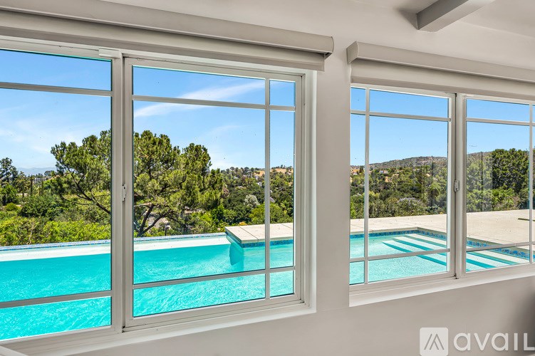 A large window overlooking a pool and trees.