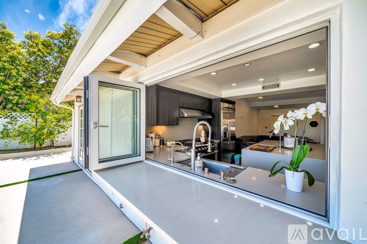 A modern kitchen with a glass door leading to a living area.