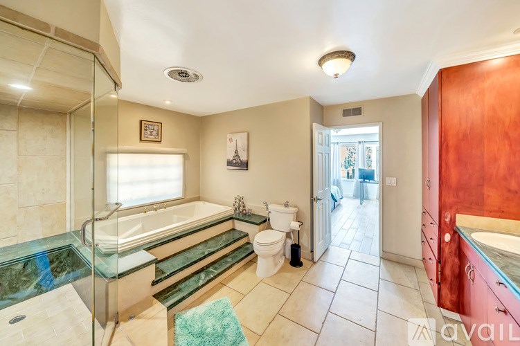 A bathroom with a glass shower stall and a toilet.