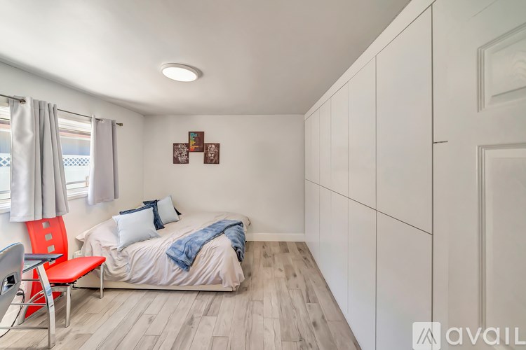 A bedroom with a bed, chair, and a window.