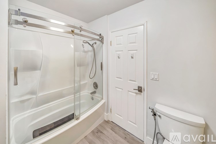 A white bathroom with a glass shower stall and a white door.