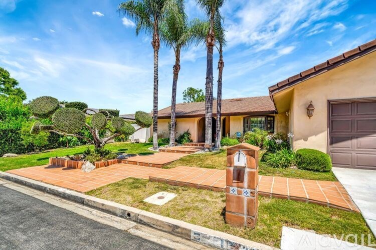 A house with a driveway and a palm tree in front.