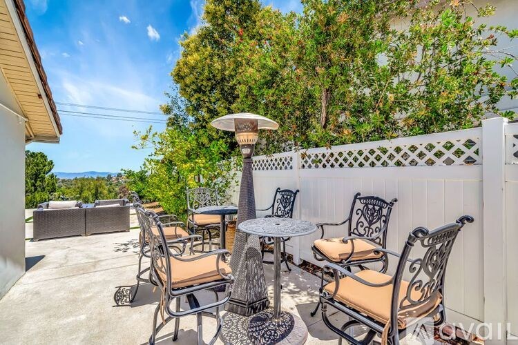 A patio with a table, chairs, and an umbrella.