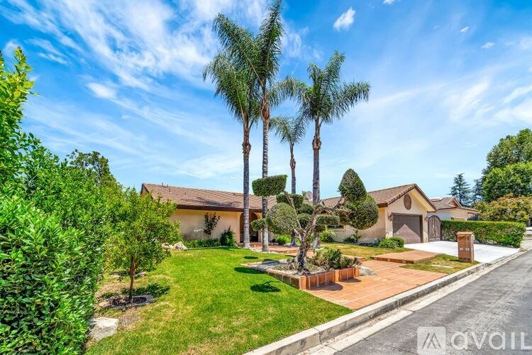 A house with a driveway and palm trees in front.