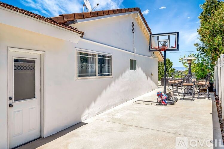 A white house with a basketball hoop in the backyard.