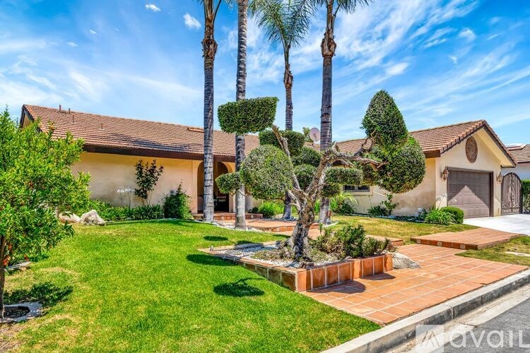 A house with a well-manicured lawn and a palm tree in front.