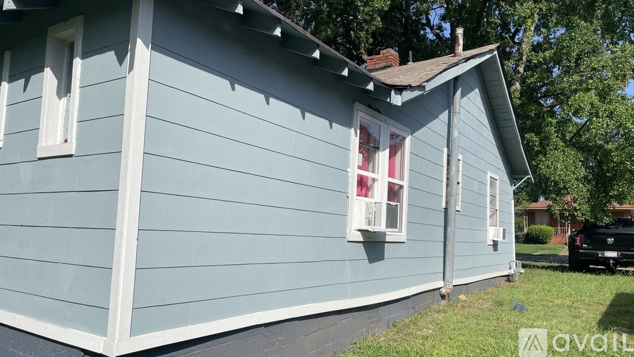 A blue house with a white window and a black car parked in the driveway.