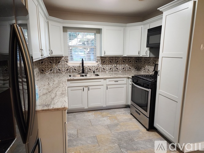 A kitchen with white cabinets and a marble countertop.