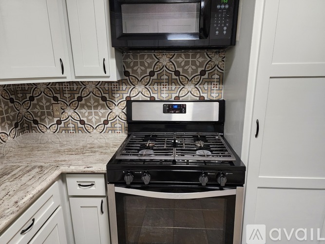 A kitchen with a black stove top oven and a microwave above it.