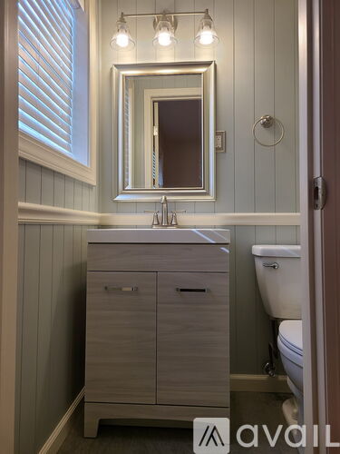 A bathroom with a sink, mirror, and cabinet.