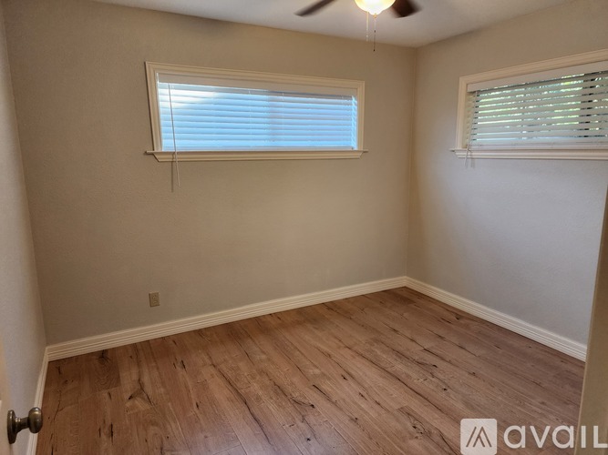 A room with wooden flooring and a window with blinds.