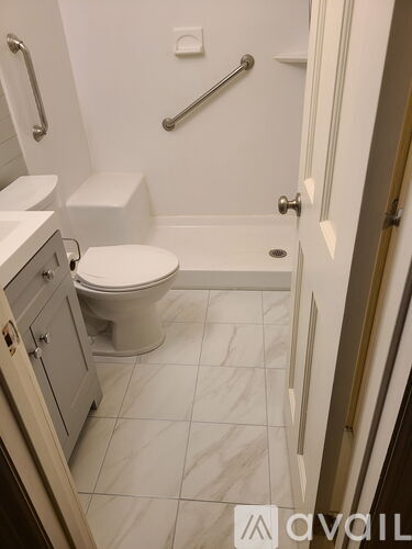 A white toilet in a small bathroom with a white tiled floor.