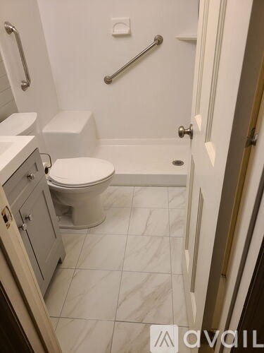 A white toilet in a small bathroom with a white tiled floor.