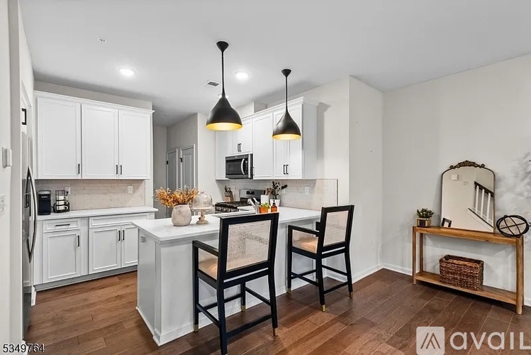 A kitchen with white cabinets and a wooden island with two chairs.