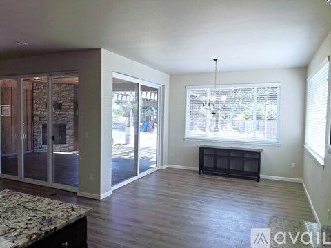 A living room with a marble table and a window with blinds.