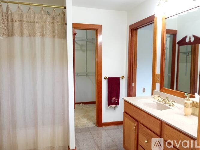 A bathroom with a shower curtain, sink, mirror, and wooden door.