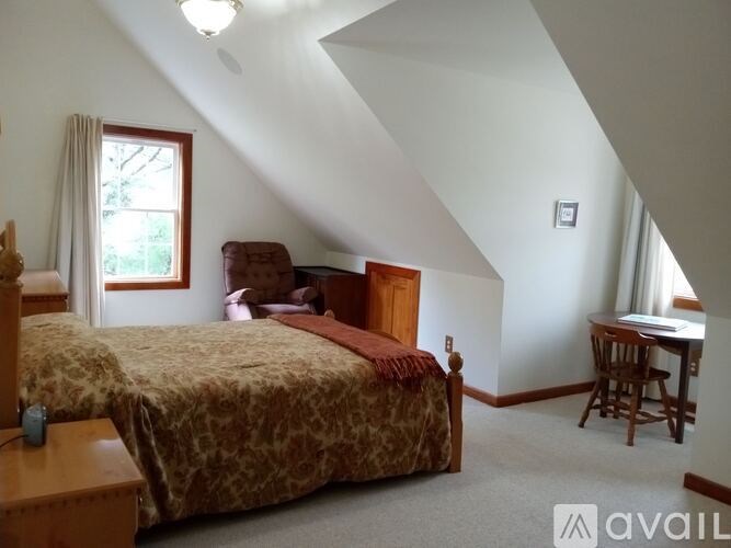 A bedroom with a bed, desk, and chair.