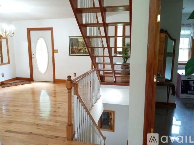 A wooden staircase with a white railing leads up to a second floor.