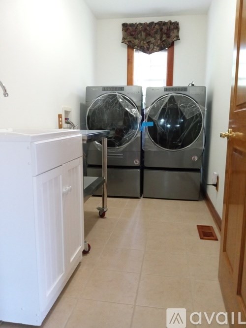 A laundry room with two washing machines and a white cabinet.