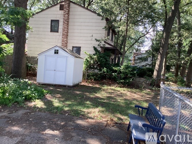A backyard with a shed, a bench, and a fence.