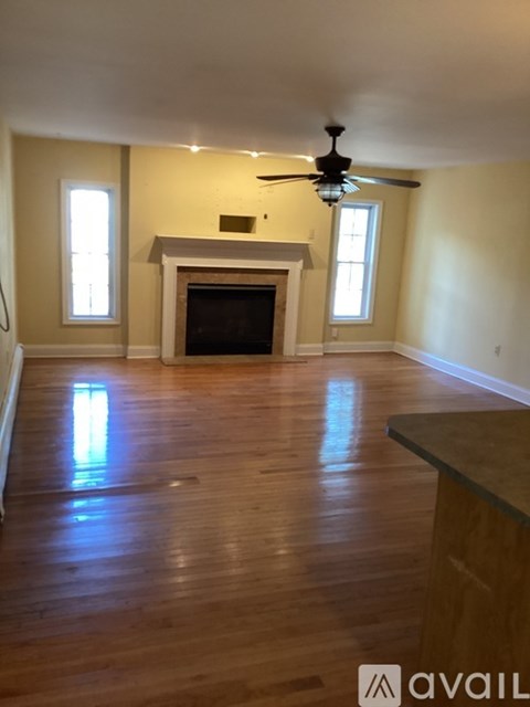 A living room with a fireplace and a ceiling fan.