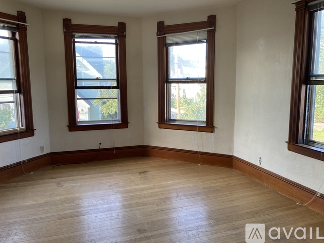 A room with wooden floors and three windows.