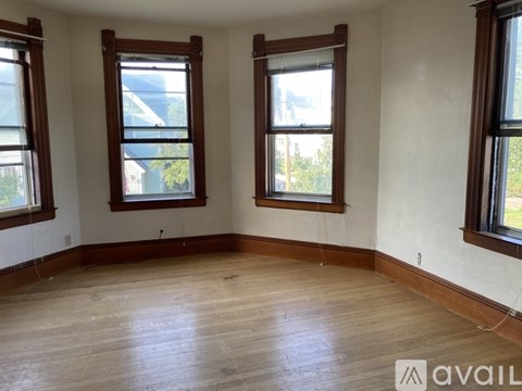 A room with wooden floors and three windows.