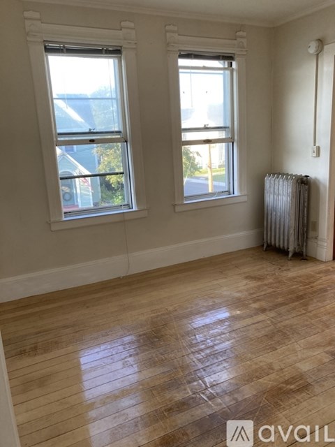 A room with wooden floors and two windows.