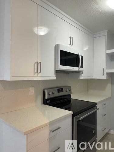 A kitchen with white cabinets and a black stove top oven.