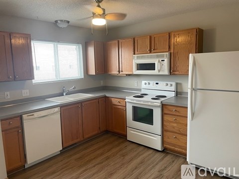 A kitchen with white appliances and wooden cabinets.