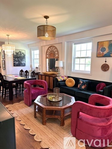A living room with a wooden coffee table and a pink chair.