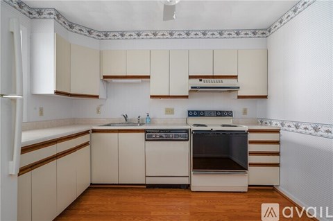A kitchen with white cabinets and a wooden floor.