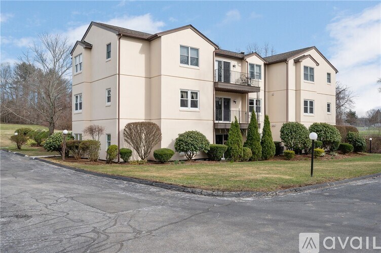 A large beige apartment building with a parking lot in front.