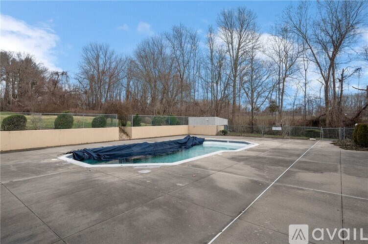 A pool covered with a blue tarp in a fenced area.