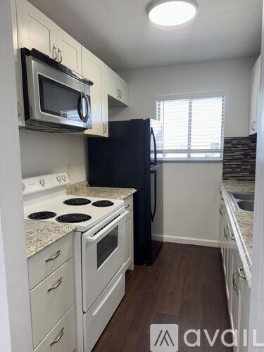 A kitchen with white cabinets and a black refrigerator.
