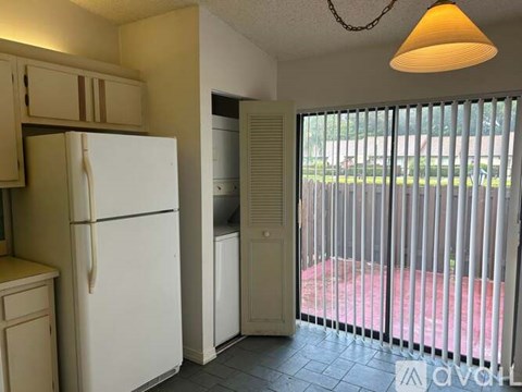 A white refrigerator is in a kitchen next to a white washer and dryer.