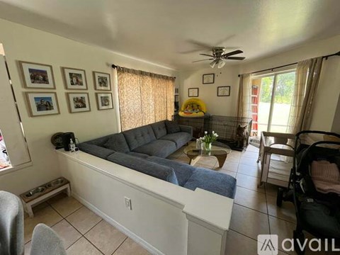 A living room with a grey couch and a ceiling fan.