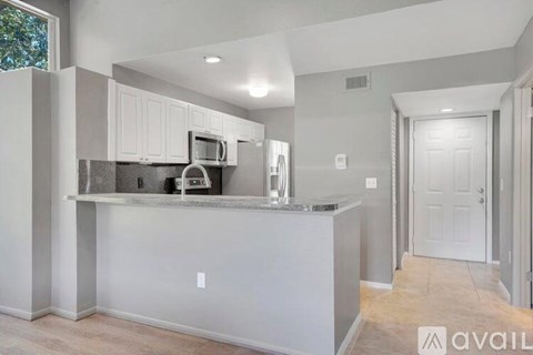 A kitchen with white cabinets and a grey island.