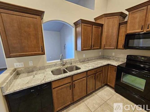 A kitchen with wooden cabinets and black appliances.